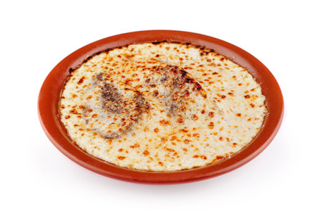 Delicious lasagna with meat and cheese baking in a rustic clay plate, isolated on white backgroundの写真素材