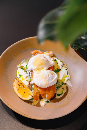 Delicious poached eggs with salmon and sauce on toasted bread are served on a plate for a healthy and nutritious breakfastの写真素材