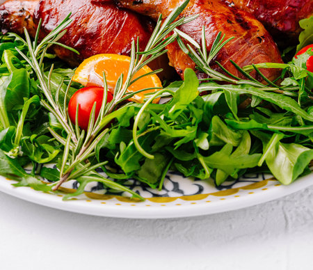 Delicious roasted chicken served with arugula salad, cherry tomatoes, and orange slicesの写真素材