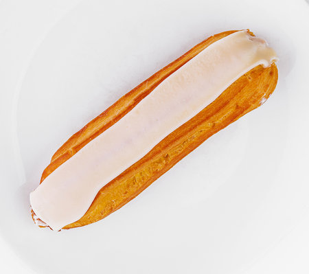 Top view of a delicious single eclair with creamy filling on a clean white surfaceの写真素材