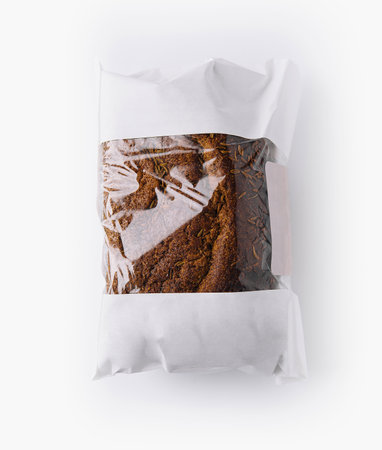 Freshly baked loaf of rye bread with cumin seeds in a paper bag with a transparent window on a white backgroundの写真素材