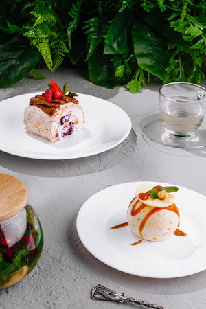 Meringue roll with strawberries and a cake ball covered in caramel are ready to be enjoyed with a glass of herbal teaの写真素材