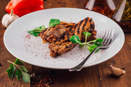 Grilled chicken breast on white plate decorated with green salad being served on wooden tableの写真素材
