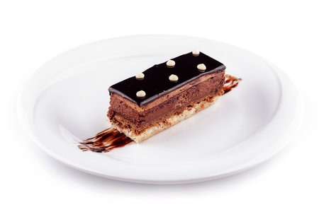 Chocolate cake on a white plate decorated with chocolate sauce, isolated on white background
