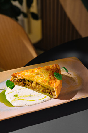 Quiche served on a plate with creamy sauce decorated with herbsの写真素材