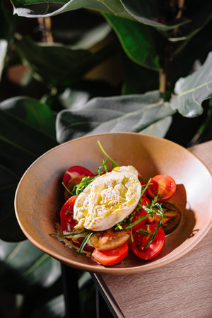 Burrata cheese salad with fresh tomatoes and arugula drizzled with olive oilの写真素材