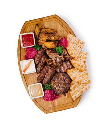Delicious grilled meat platter with various sauces served on a wooden board, perfect for sharing with friends and familyの写真素材