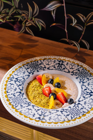 Oatmeal porridge topped with chopped fruits like strawberries, blueberries and banana slices with crushed pistachiosの写真素材