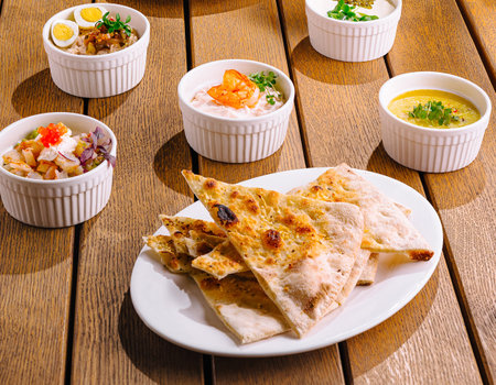 Spread of delicious mediterranean dishes artfully displayed on a warm wooden backgroundの写真素材