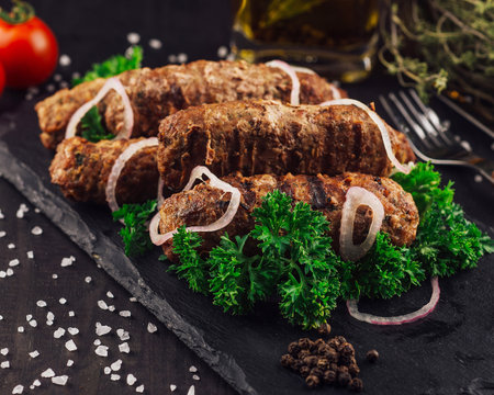 Delicious kebabs with red onions and herbs on a black slate platter, seasoned with salt and pepperの写真素材