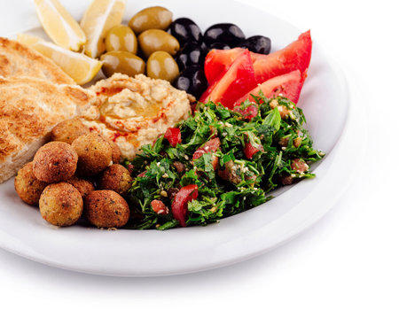 Plate of delicious middle eastern food presenting pita bread, falafel, hummus, tabbouleh, olives and tomatoesの写真素材