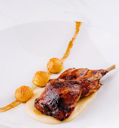 Roasted chicken legs are served on white plate with mashed potatoes and crispy ballsの写真素材