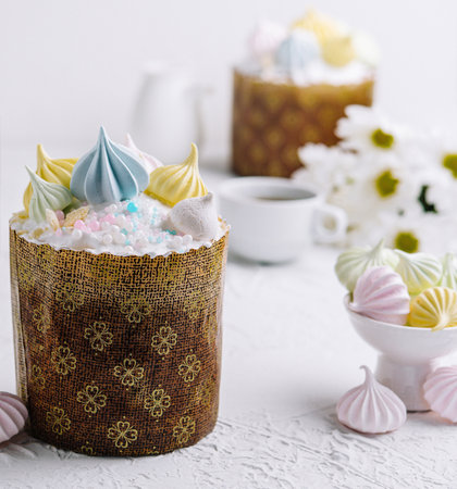 Traditional easter kulich cake topped with pastel meringues and sprinkles, with festive decorの写真素材