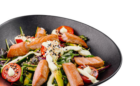 Fresh and healthy salad with salmon, tomatoes, arugula and creamy sauce served in a black bowl on white backgroundの写真素材