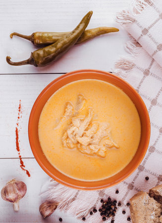 Traditional tripe soup is served in a rustic bowl with spices on a white wooden tableの写真素材