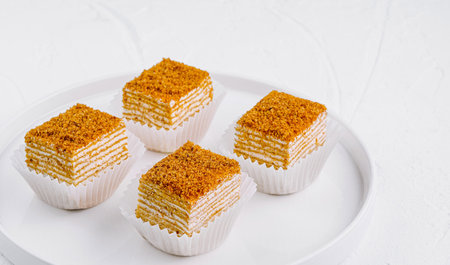 Four honey cake slices with crumb topping sitting on white plate on white backgroundの写真素材