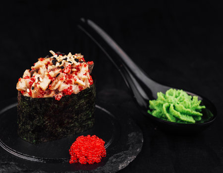 Gunkan maki sushi with spicy seafood salad, tobiko and sesame seeds on black backgroundの写真素材