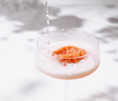 Refreshing summer cocktail being prepared by a bartender adding sparkling wine in a glassの写真素材