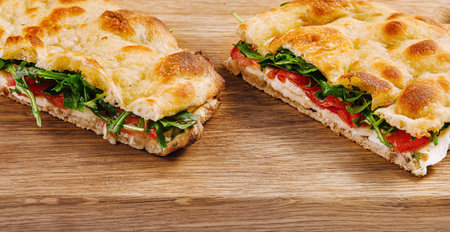 Sliced italian panini with vegetables and cheese on a cutting board close upの写真素材