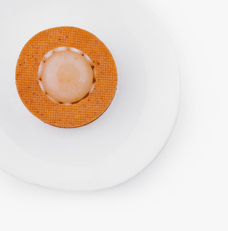 Single orange sphere centered on a textured mat against a white backgroundの写真素材