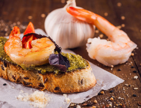 Delicious bruschetta with shrimps and pesto sauce being served on rustic wooden tableの写真素材