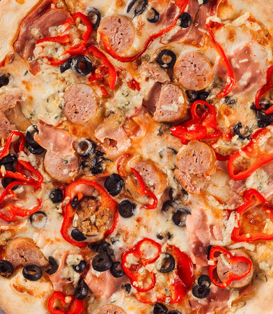 Freshly baked pizza featuring melted mozzarella cheese, savory sausage, sliced bell peppers, and olives, creating a tempting culinary delightの写真素材