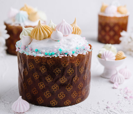 Traditional easter cake adorned with colorful meringue kisses and sprinkles on a white background