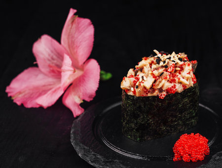 Gunkan maki sushi with spicy seafood salad, tobiko and sesame seeds on black backgroundの写真素材