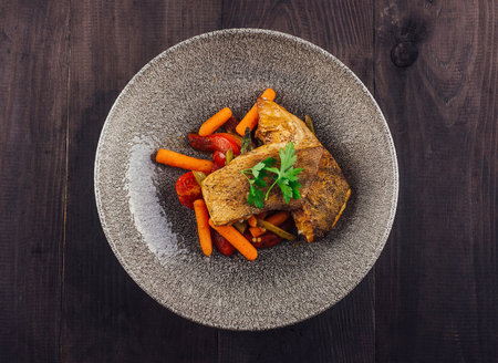 Delicious grilled fish fillet served with carrots, tomatoes, green beans and parsley on a plateの写真素材