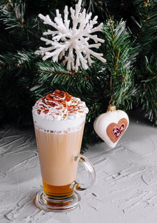 Delicious latte with whipped cream near a decorated christmas tree, capturing the cozy holiday...