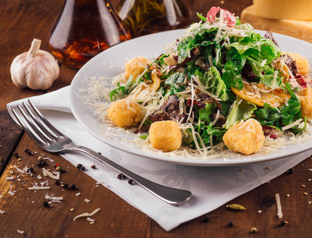 Fresh salad with lettuce, croutons, meat and parmesan cheese on a white plateの写真素材