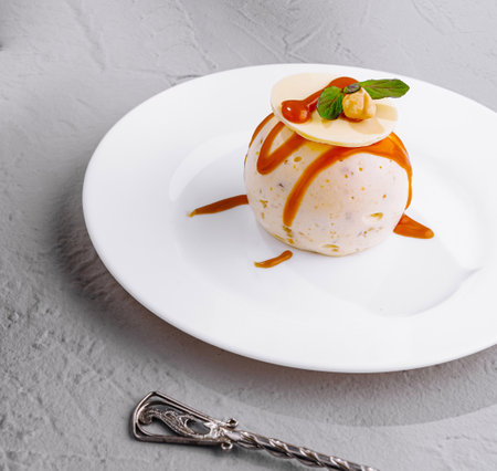 Round cake with caramel and hazelnuts lying on a white plate is waiting for a client in a restaurantの写真素材