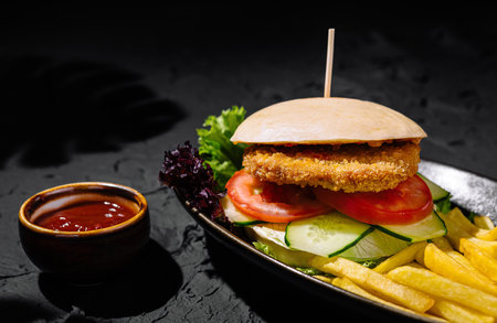 Delectable chicken burger served with golden fries and ketchup, perfect for a tasty mealの写真素材
