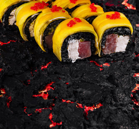 Gourmet sushi roll with mango and caviar on a bed of black rice, showcasing a fusion of flavorsの写真素材