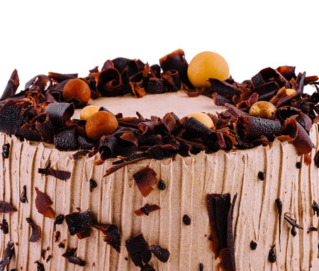 Whole chocolate cake is decorated with chocolate shavings and round candiesの写真素材