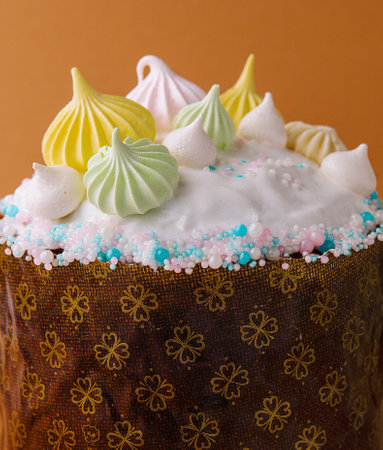 Vibrant cake adorned with multicolored meringue kisses and sprinkles on a floral base