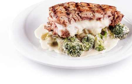 Grilled chicken breast stuffed with cheese is served on a white plate with broccoliの写真素材
