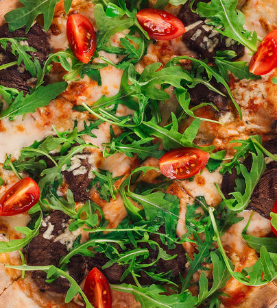 Delicious hot pizza with mushrooms and arugula close up backgroundの写真素材