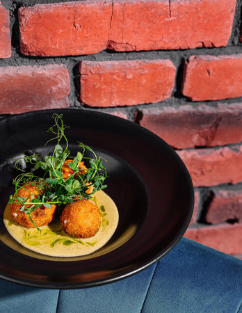 Delicious fried delicacies served on a black plate against a red brick wall backdrop