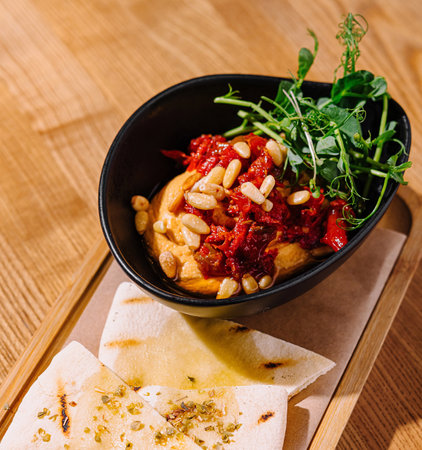 Vibrant bowl of hummus topped with legumes and herbs served with spiced flatbreadの写真素材