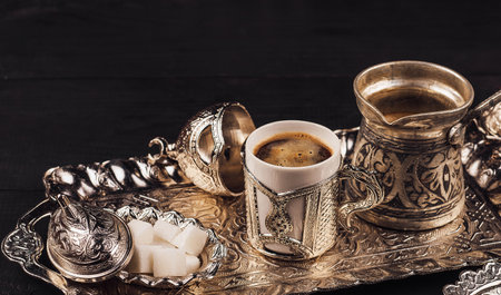 Silver coffee set with sugar and cezve standing on a silver tray on a dark wooden tableの写真素材