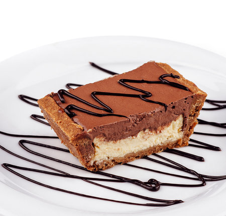 Delicious chocolate tartlet sitting on a white plate decorated with chocolate sauce