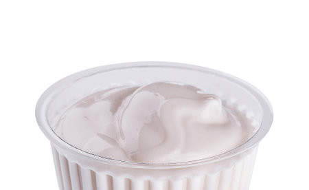 Close-up shot of creamy yogurt in a disposable cup with a white backgroundの写真素材