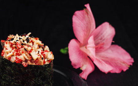 Gunkan maki sushi with spicy seafood salad, tobiko and sesame seeds on black backgroundの写真素材