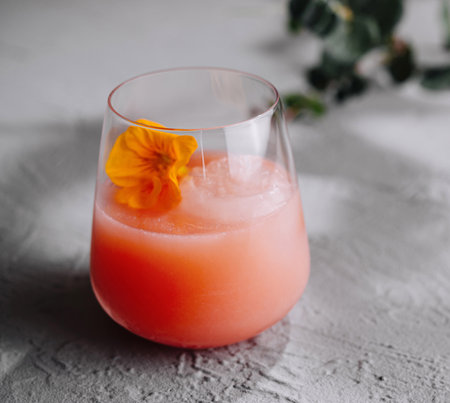 Refreshing pink beverage in a modern glass, adorned with a delicate edible flowerの写真素材