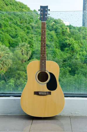 Wood guitar against wall glass ,background and texture