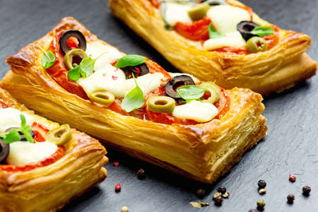 Puff pastry with tomatoes, mozzarella cheese, olives and marjoramの写真素材