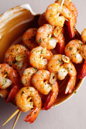 Spicy fried shrimps with garlic and herbs on bamboo skewersの写真素材
