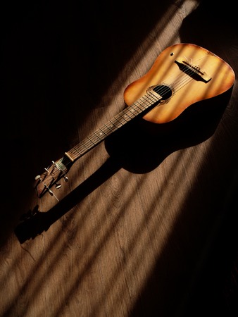 Classical guitar on wooden background long shadowsの写真素材