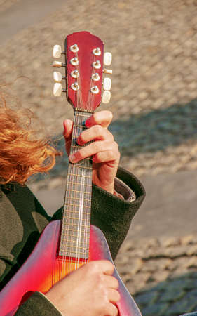 A young man plays the mandolin in the city on the street. close-up hands.